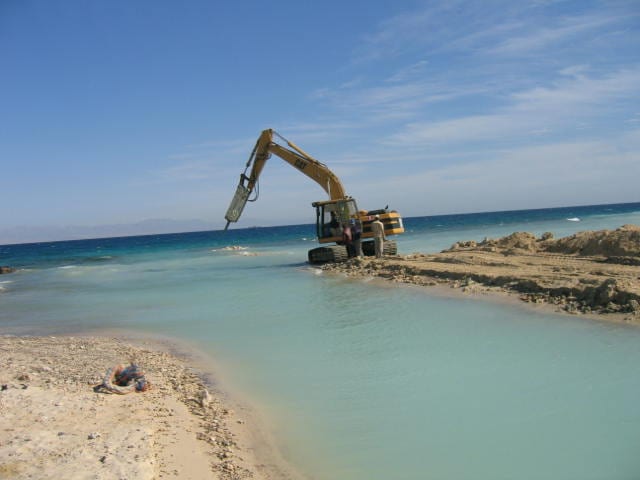 Excavator working from the temporary causeway at the water line.