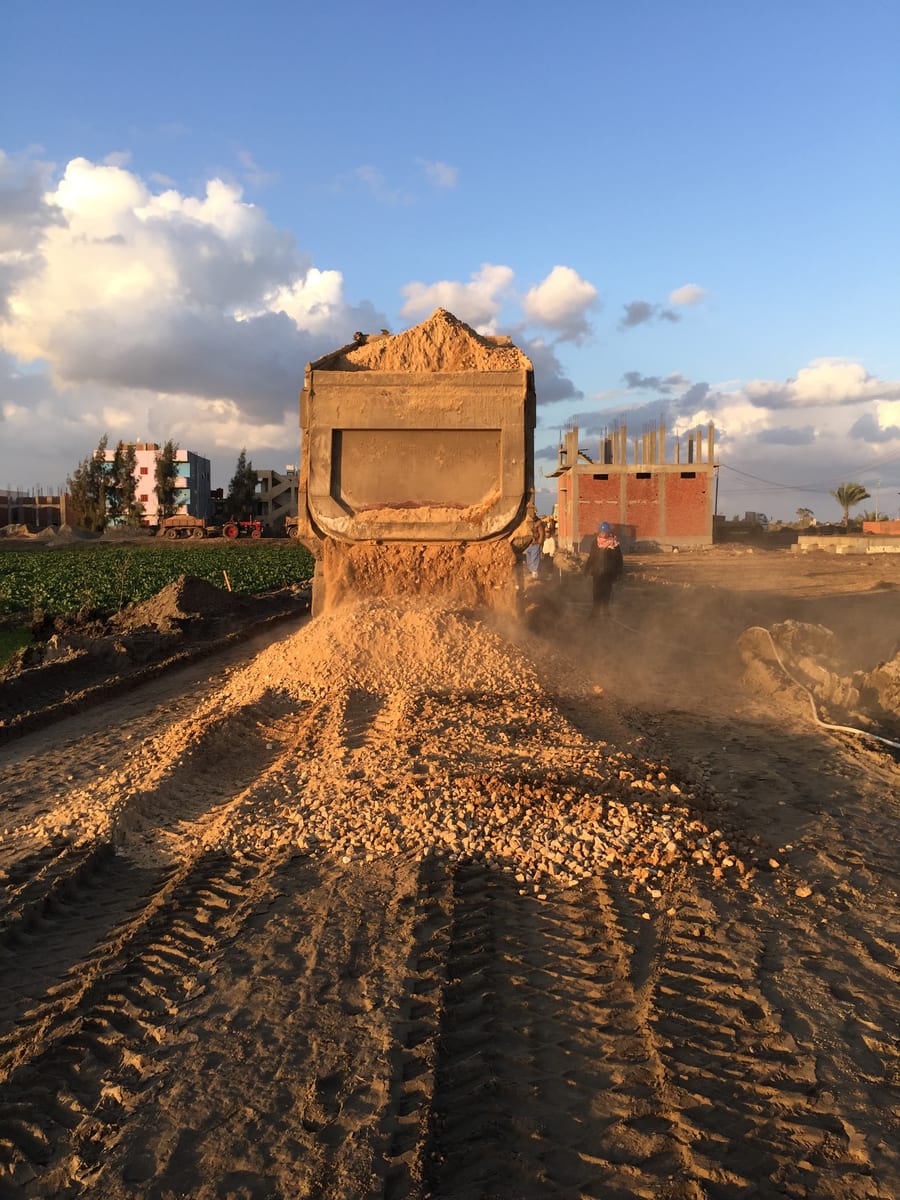 Fill material delivered to build an access road in farmland.