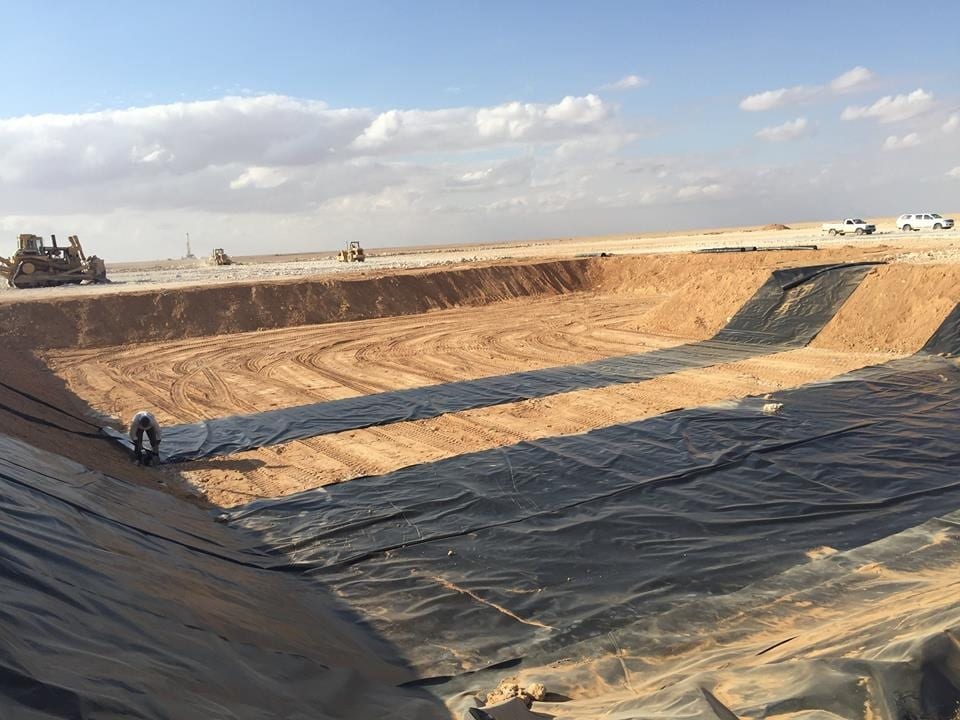 Plastic sheet being laid in a pit.